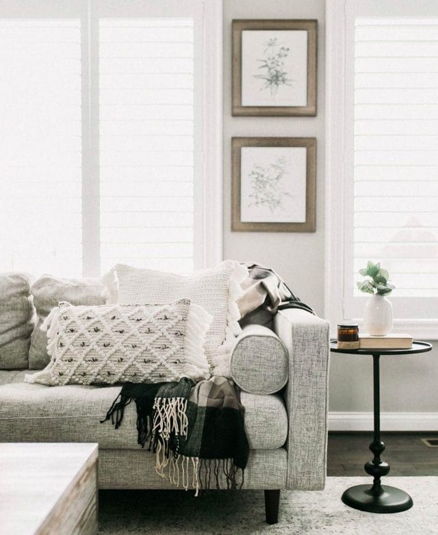 A Sven Birch Ivory fabric sofa is draped with throws and throw pillows in the home of blogger Our Dwelling Place.